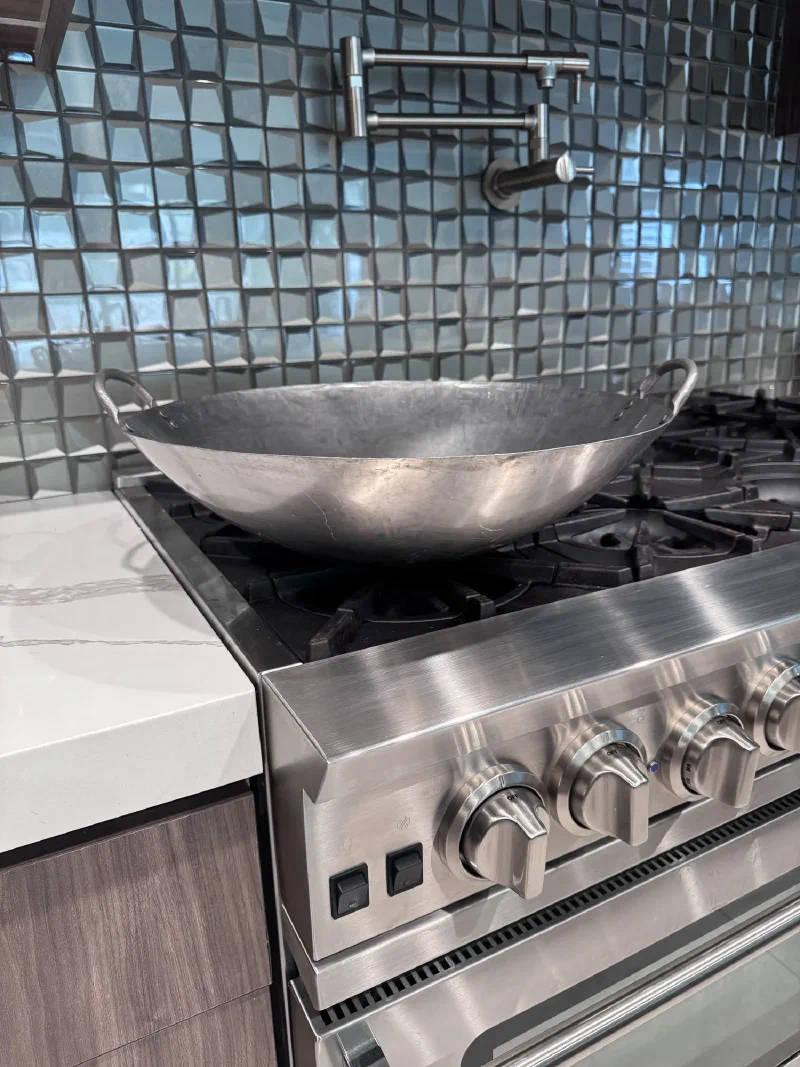 A seasoned carbon steel wok on a professional gas range